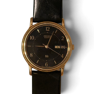 Primer plano de la esfera negra del Seiko SQ 5H23-6280, con índices de barra dorados y el día y la fecha en inglés a las tres