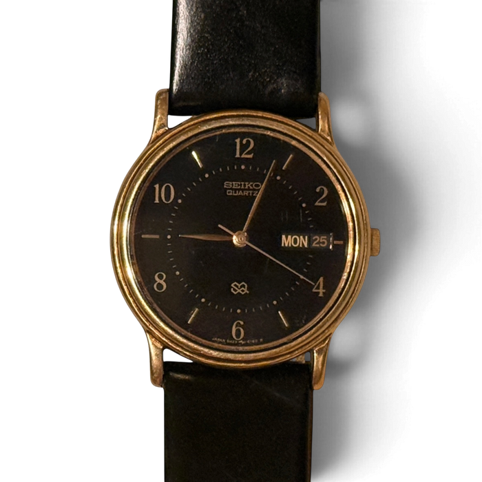 Close-up of the Seiko SQ 5H23-6280 black dial, gold baton markers and English day-date at three